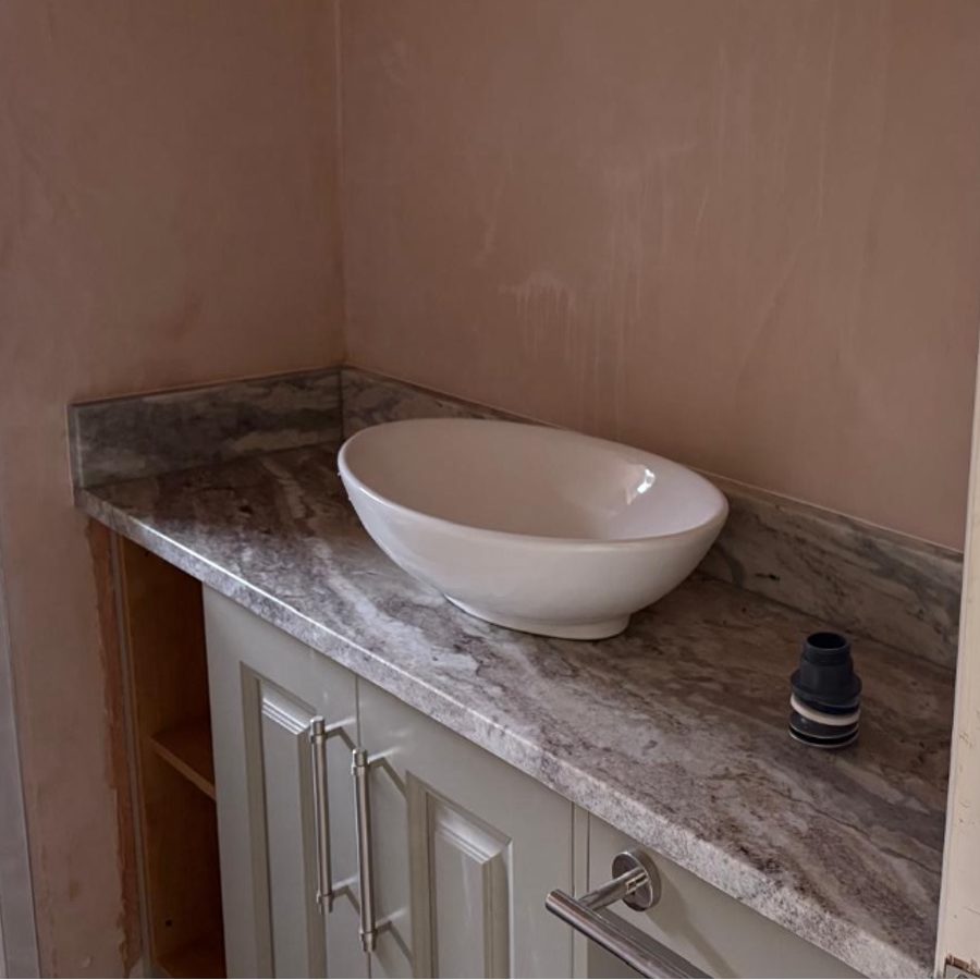 Cloakroom vanity in bare pink plaster, with the basin dry-fitted and no tap or waste connected
