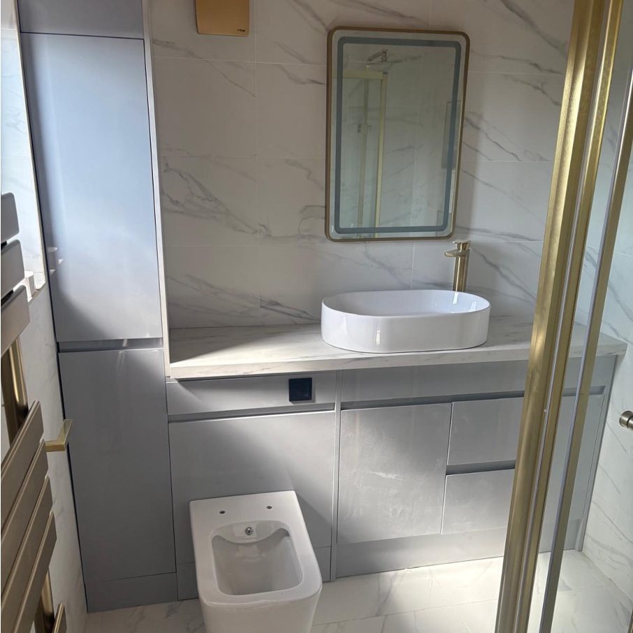 Finished bathroom with a countertop basin, brushed gold tap, mirror and back-to-wall WC by AGG Renovations
