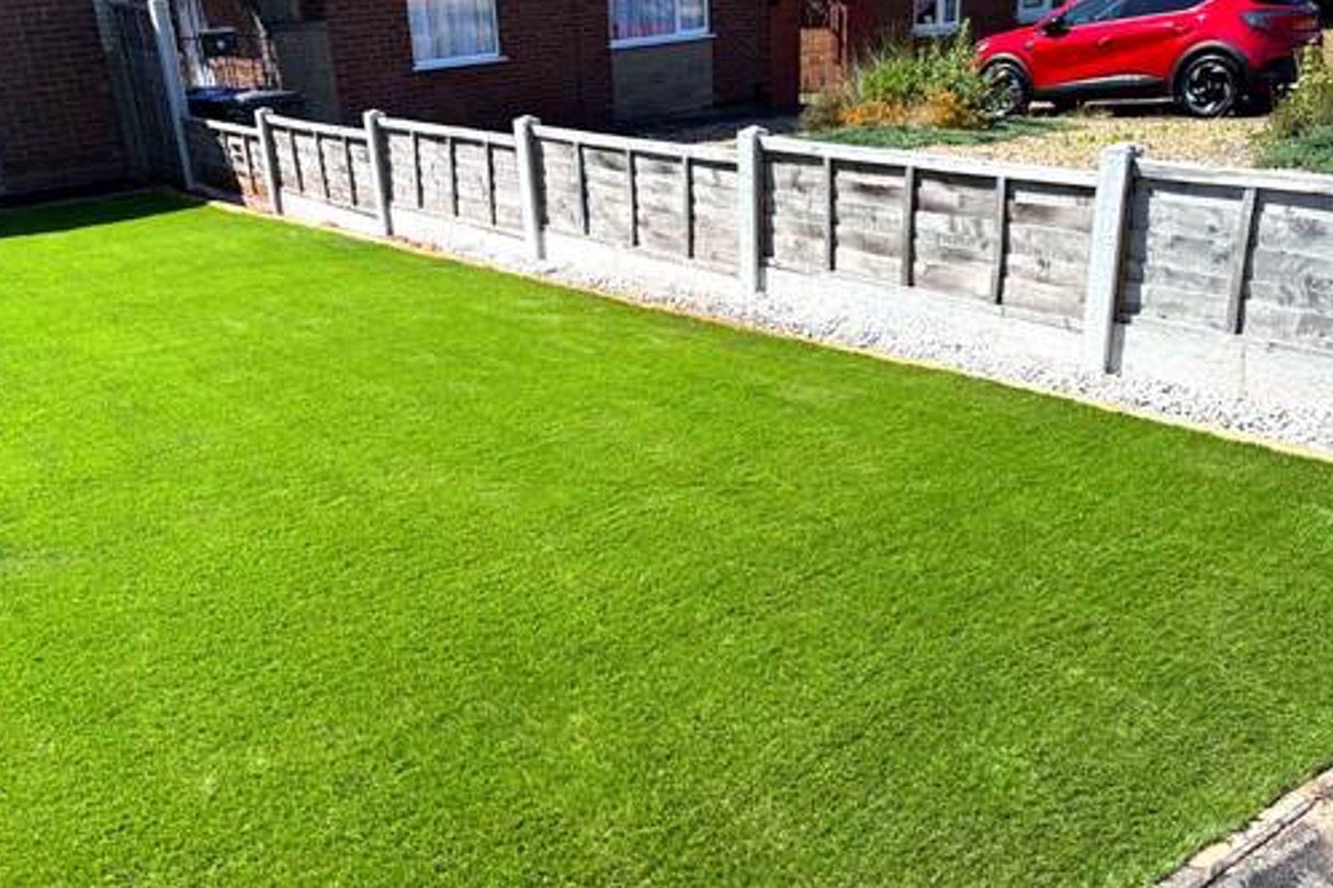 Front garden laid with artificial grass and a gravel edge along the fence line by AGG Renovations