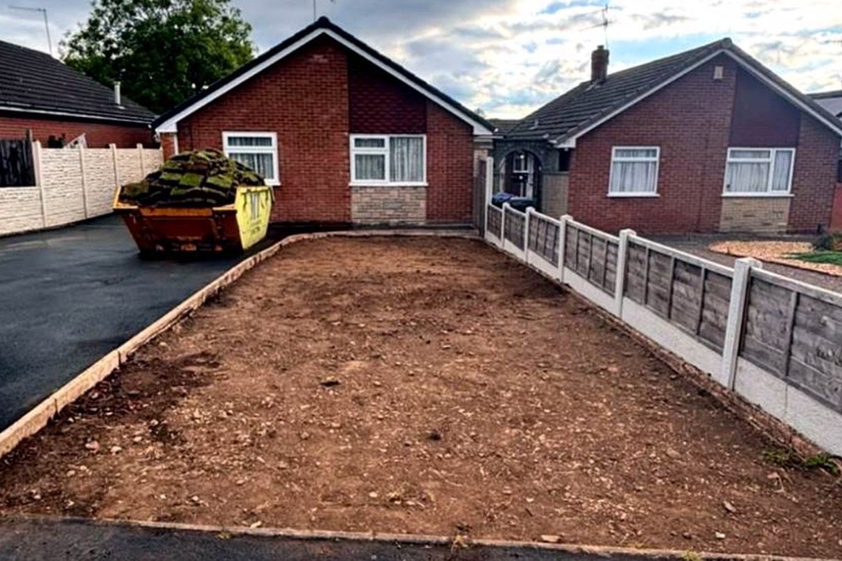 Front garden stripped back to bare soil with the old turf loaded into a skip