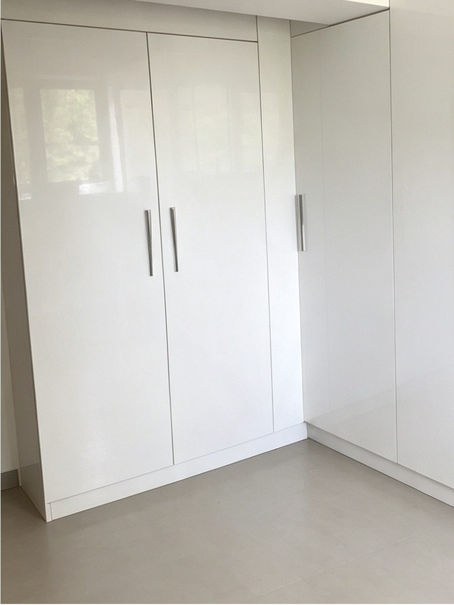 Finished corner wardrobes in white gloss with brushed steel handles by AGG Renovations