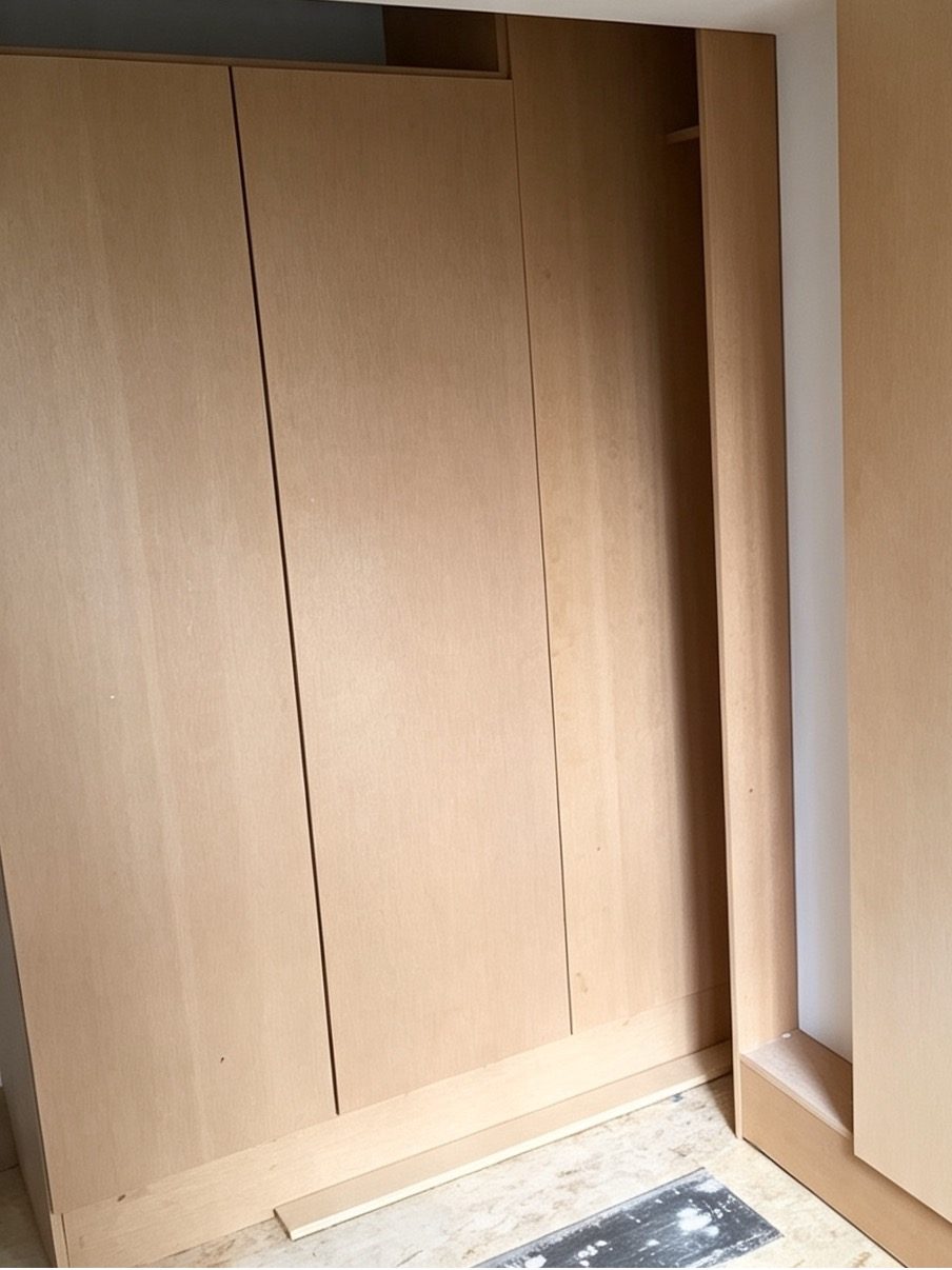 Corner run of wardrobes in bare veneered board, doors hung but unpainted