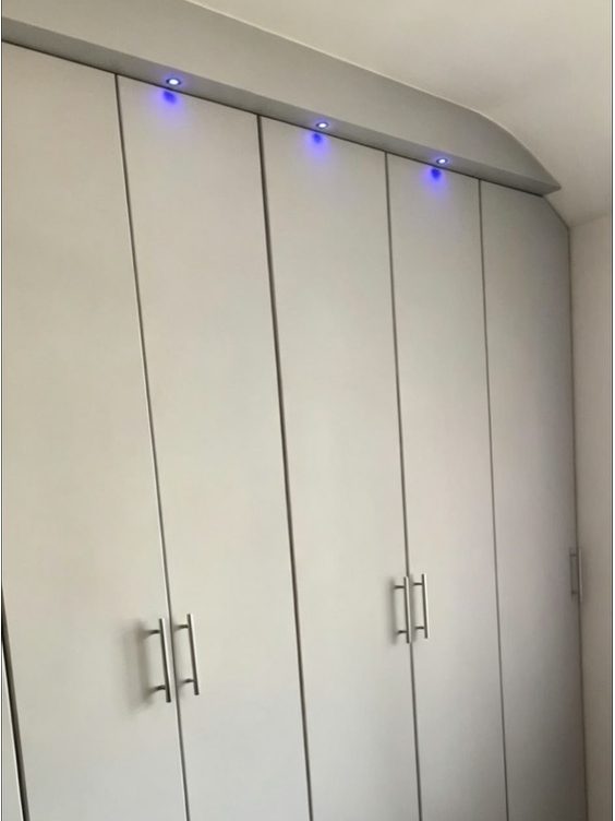 Finished fitted wardrobes sprayed soft grey with long handles and a lit pelmet by AGG Renovations