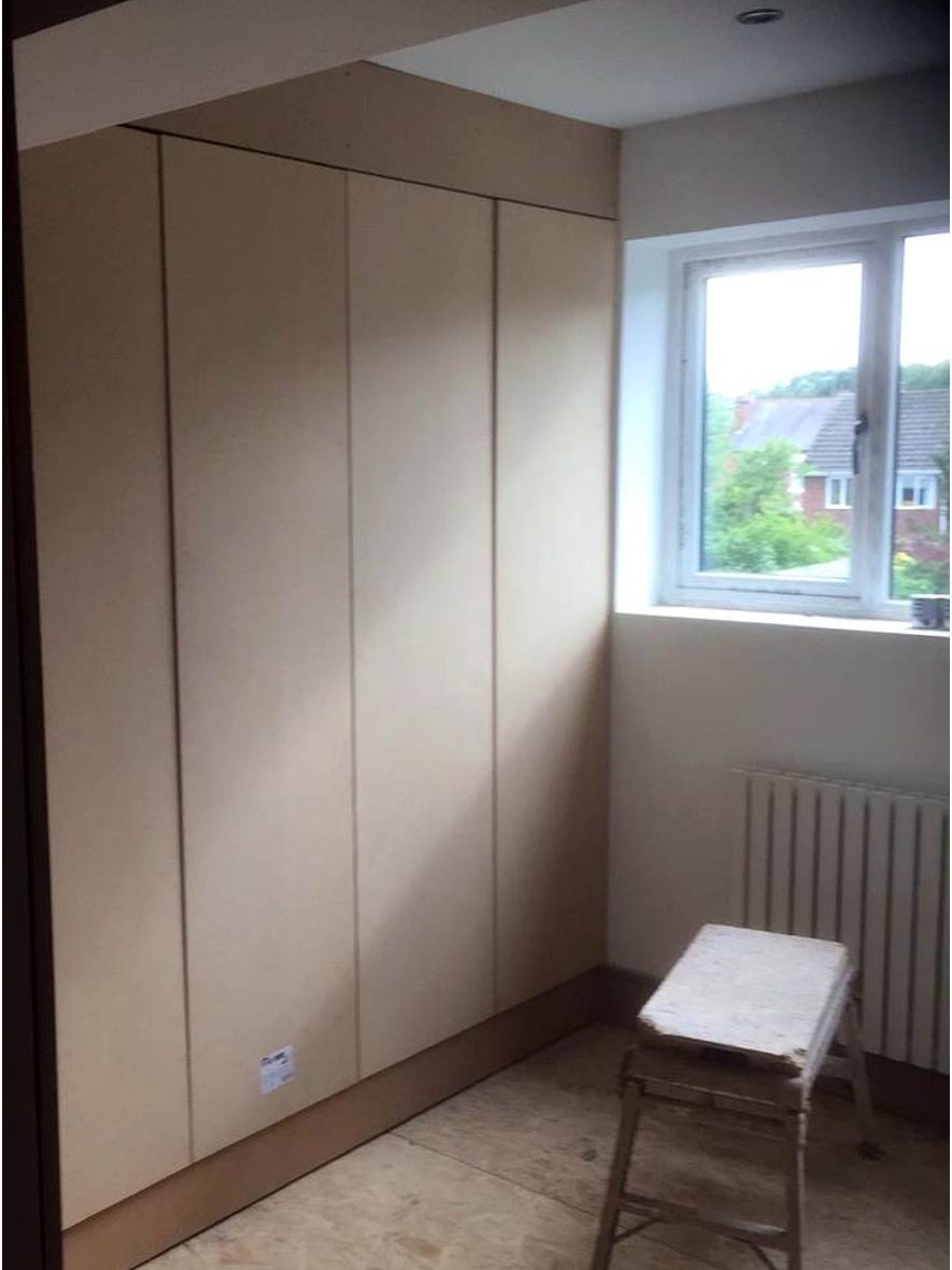 Fitted wardrobe built into the alcove in bare board, before painting, with the floor still unfinished