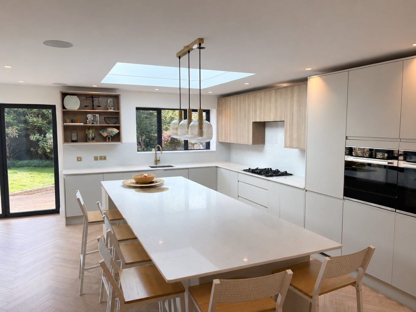 Finished handleless kitchen with a quartz island, breakfast seating and herringbone flooring by AGG Renovations