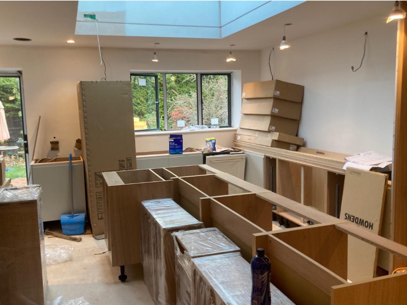 Kitchen mid-fit with bare carcasses, flat-packed units and a new roof lantern overhead