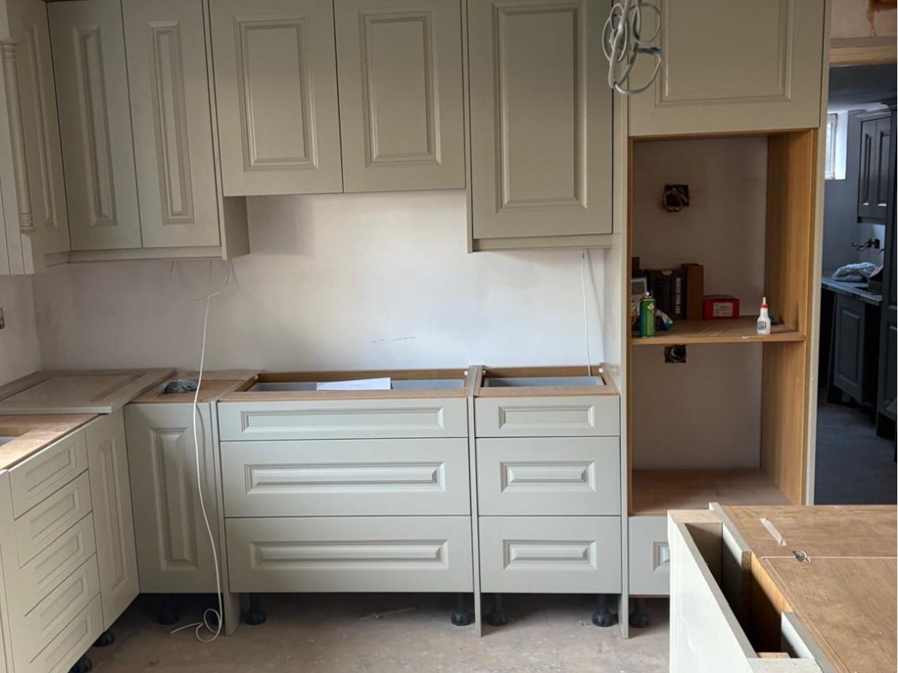 Sage shaker units part-fitted with bare chipboard tops and no worktops