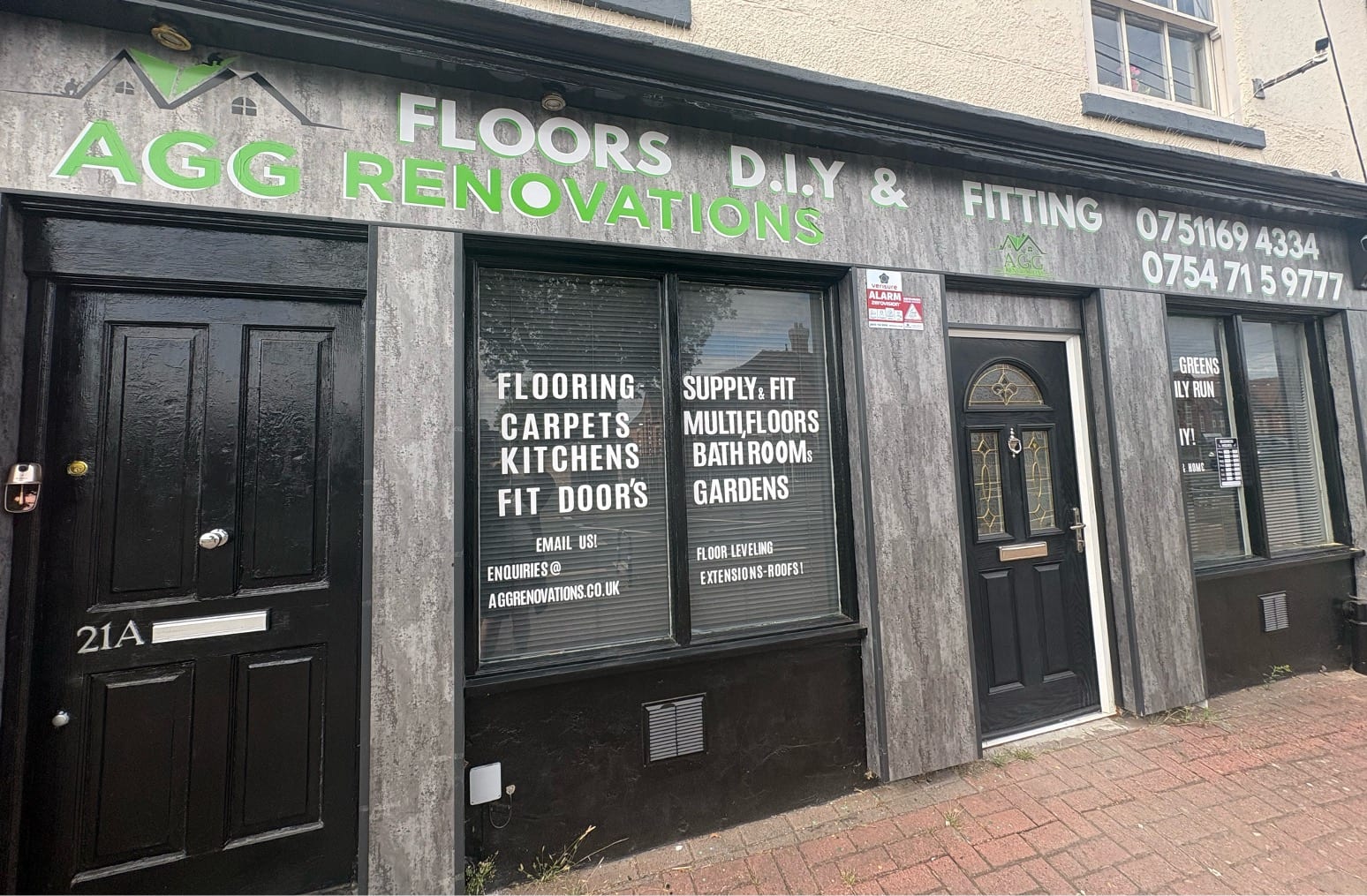 The finished AGG Renovations shopfront: dark timber-effect cladding, green signwriting reading Floors, DIY and Fitting, new composite doors and window graphics listing the trades