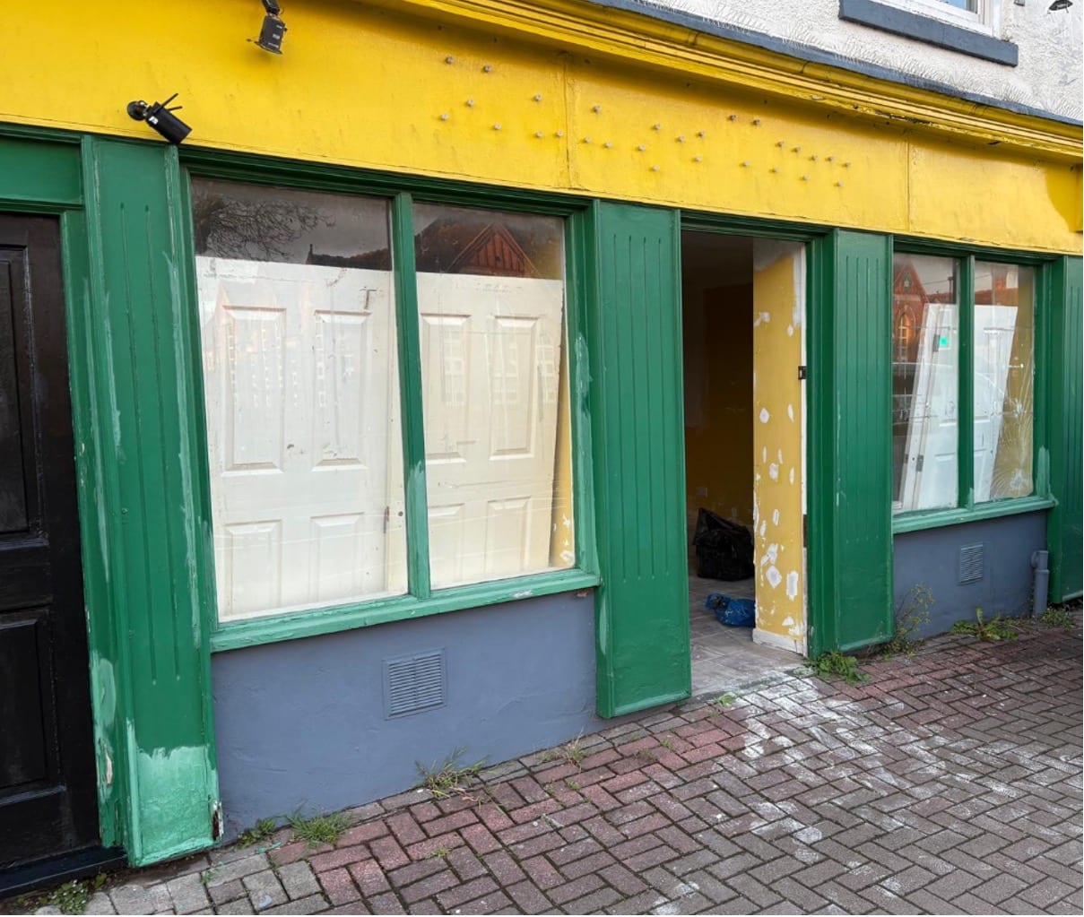 21 Bilston Street before AGG Renovations took it on: flaking yellow and green paintwork, windows papered over from inside and old doors stacked against the glass