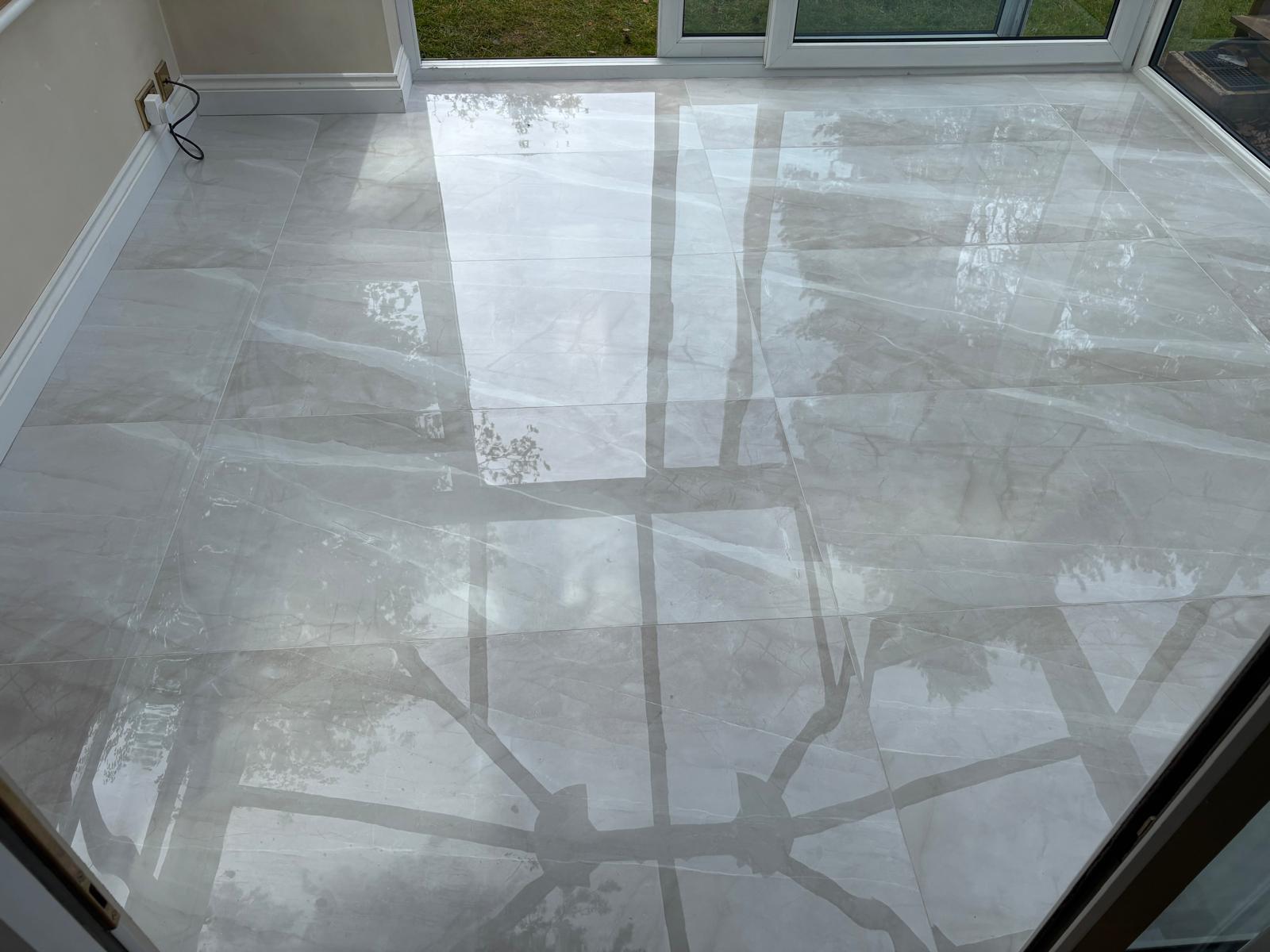 Large-format polished porcelain floor tiles laid through a garden room by AGG Renovations